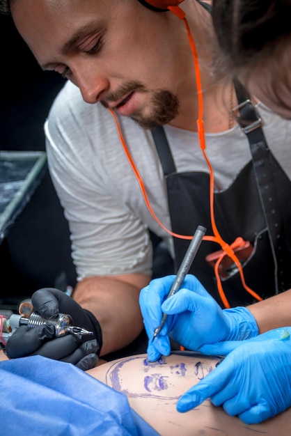 Tattoo artist making a tattoo in tattoo parlour./Tattooer makes tattoo in tattoo parlor.