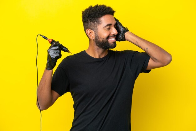 Tattoo artist man Brazilian man isolated on yellow background smiling a lot