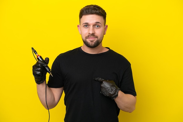 Tattoo artist man isolated on yellow background with surprise facial expression