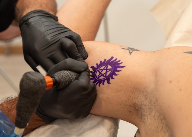 Foto artista del tatuaggio che esegue un tatuaggio su un cliente