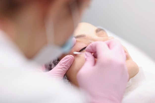 Tattoo artist prepares eyelids for procedure permanent eye makeup concept