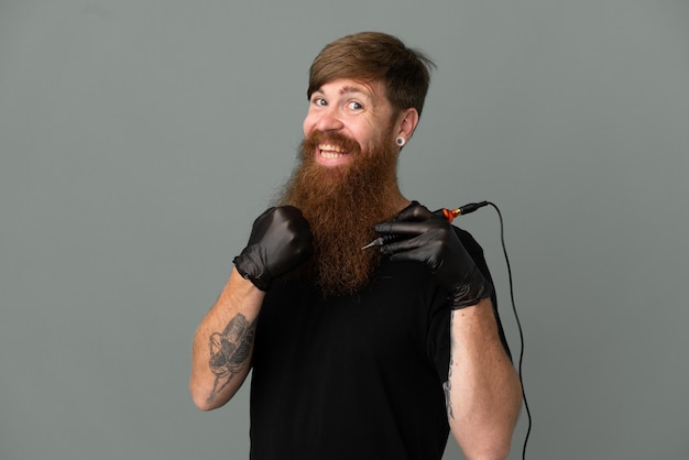 Tattoo artist redhead man isolated on blue background celebrating a victory