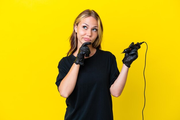 Tattoo artist Russian woman isolated on yellow background and looking up