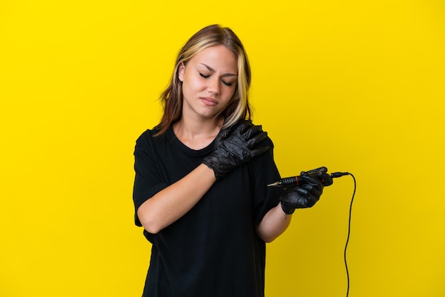 Tattoo artist Russian woman isolated on yellow background suffering from pain in shoulder for having made an effort