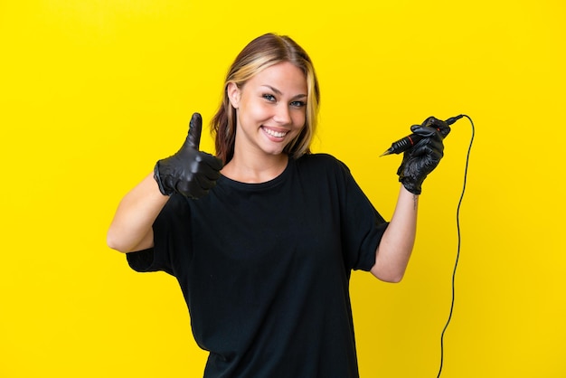 Tattoo artist Russian woman isolated on yellow background with thumbs up because something good has happened