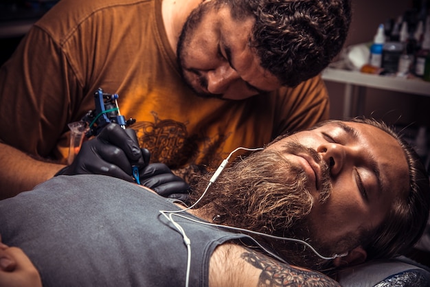 Tatuatore che mostra il processo di realizzazione di un tatuaggio nel salone del tatuaggio