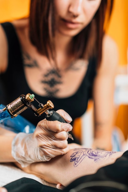 Photo tattoo artist tattooing man's arm in studio