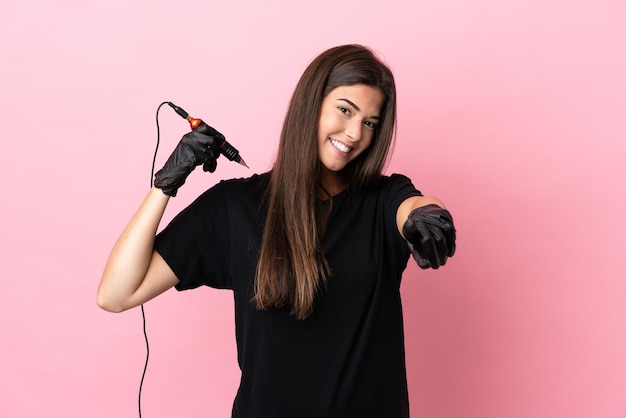 Tattoo artist woman isolated on pink background pointing front with happy expression