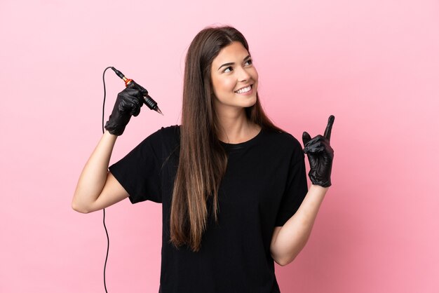 Tattoo artist woman isolated on pink background pointing up a great idea