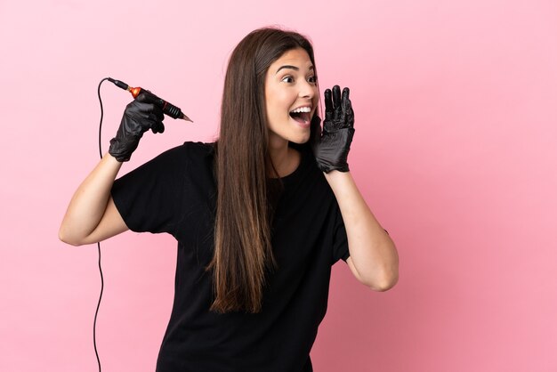 Tattoo artist woman isolated on pink background shouting with mouth wide open to the side