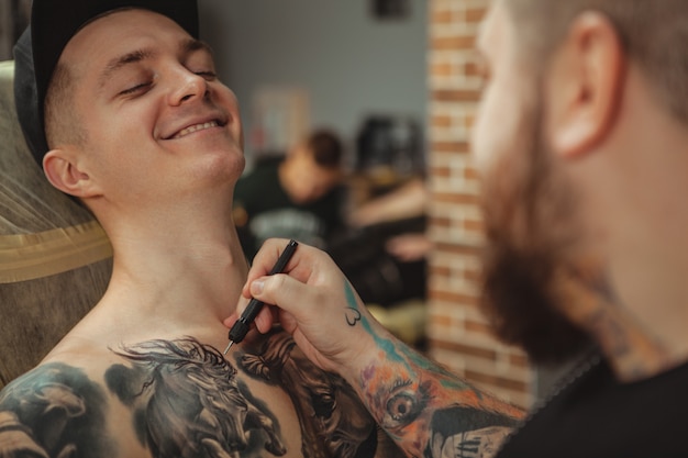 Tattoo artist working with his client at art studio