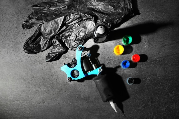 Tattoo machine and tattoo supplies on dark background