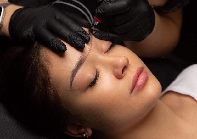 Tattoo master applying permanent makeup to a woman