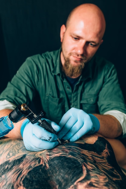 Tattoo master artist makes a tattoo. Closeup