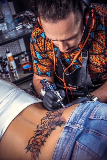 Tattoo master create tattoo in tattoo parlour./Professional tattoo artist makes tattoo pictures in studio.