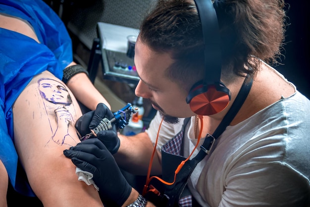 Tattoo master maakt een tatoeage op de huid in zijn salon./Tattooer maakt een tatoeage in tattoo studio.