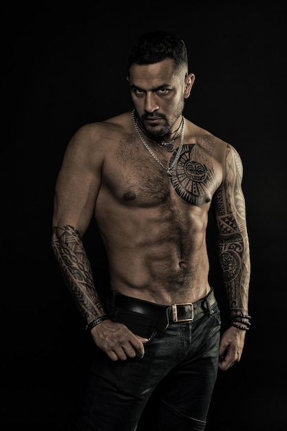 Modello tatuato con addominali e addominali uomo barbuto con corpo tatuato uomo con torso nudo sexy in jeans atleta o sportivo con petto e pancia muscolosi filtro vintage per sport o fitness e cura del corpo