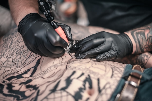 Tattoo specialist bezig met professionele tattoo machinegeweer in de salon.