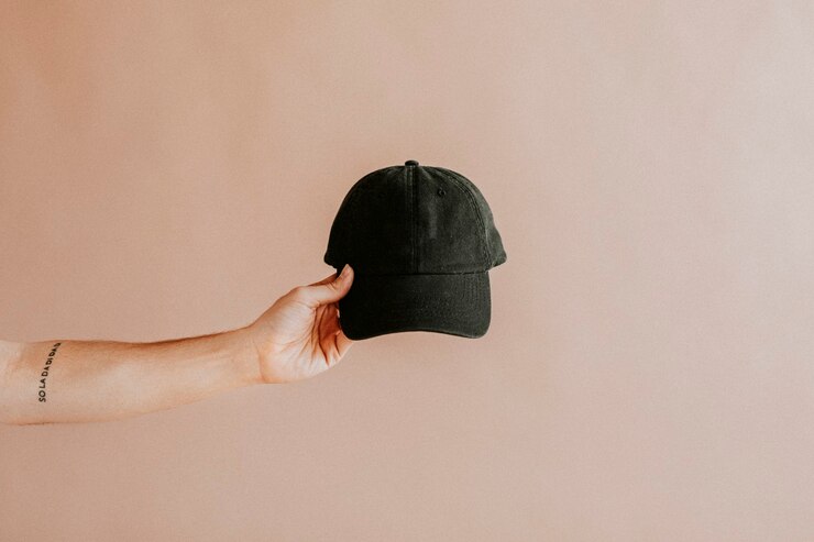 Photo tattooed arm holding a black cap