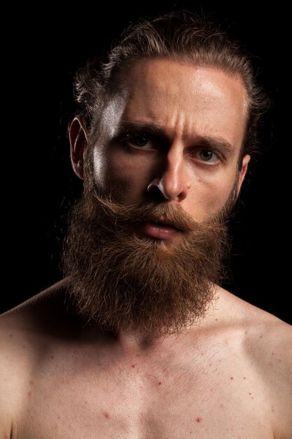 Tattooed bearded hipster on black background in studio photo. Expression and fashion