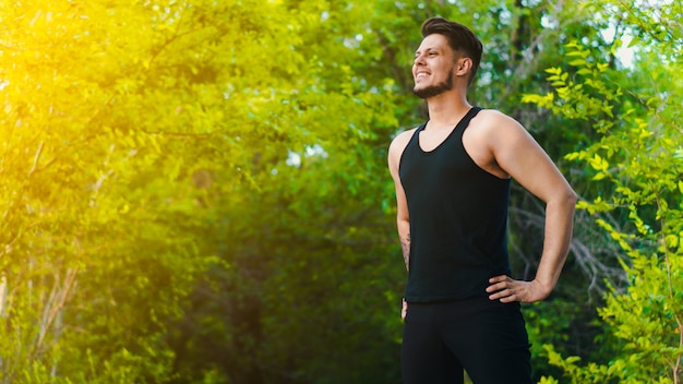Photo tattooed bearded young man exercising in park before jogging. copy space. panoramic
