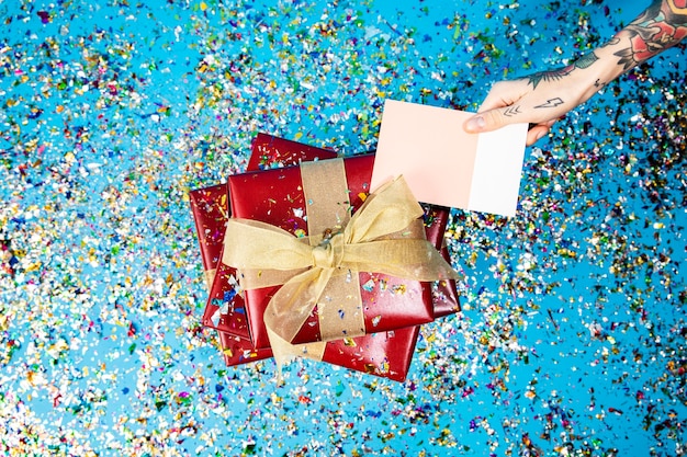 Photo tattooed hand holding a card with red gift boxes