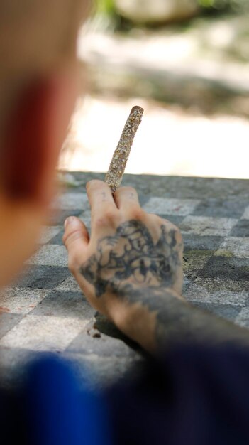 Foto una mano tatuata che tiene una marijuana blunt in un parco all'aperto