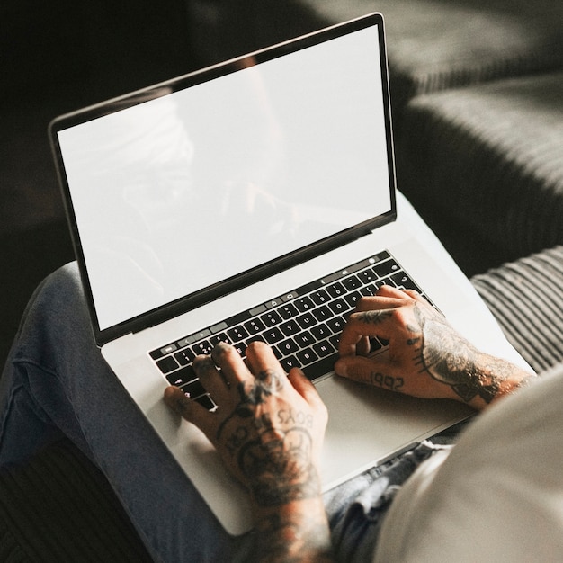 Tattooed man working on laptop screen