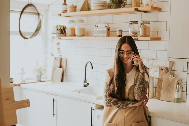 Tattooed woman in kitchen in a phone call