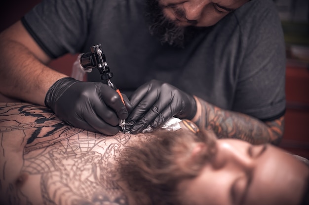 Tattooer demonstrates the process of getting tattoo in tattoo studio.