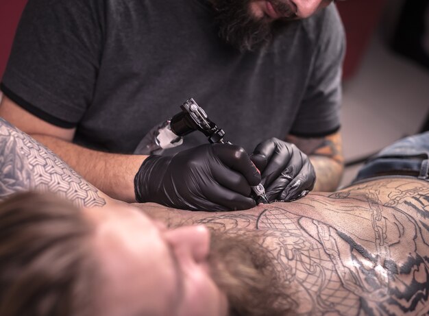 Tattooer demonstrates process of making a tattoo tatoo salon.