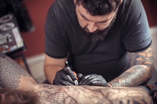 Tattooer doing tattoo picture in tattoo parlour.