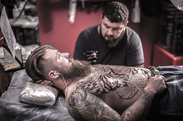 Tattooer makes tattoo pictures in tattoo studio