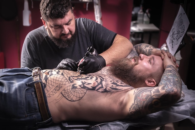 Tattooist demonstrates the process of getting tattoo in tattoo parlor