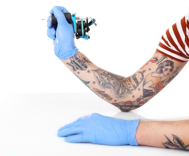 Tattooist hand in blue glove with tattoo machine isolated on white background close up