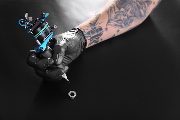 Foto tattooist hand in medische handschoen met tatoeage-machine op zwarte achtergrond