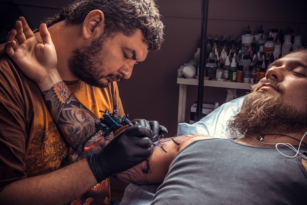 Tattooist makes tattoo in tatoo salon