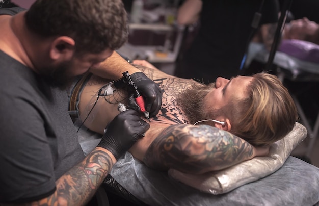 Tattooist making tattoo art in a workshop studioProfessional tattooer at work in salon