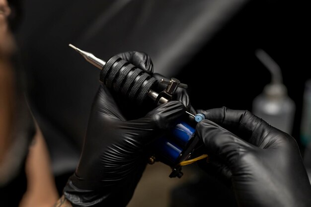 Tattooist setting up and adjusting his tattoo machine Wearing black gloves Body art concept