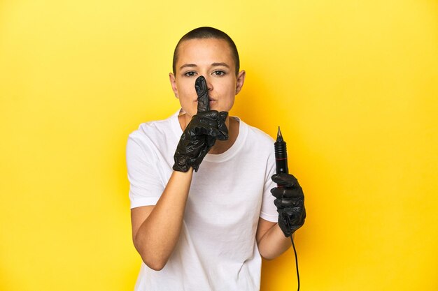 Foto donna tatuatrice in studio con testa rasata sfondo giallo che mantiene un segreto o chiede silenzio