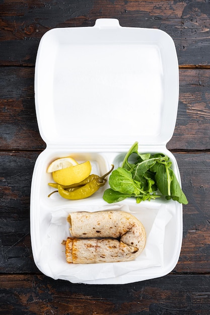 Foto tavuk tantuni durum turkse keuken doner kebab in plastic verpakking container levering lunchbox op oude donkere houten tafel achtergrond bovenaanzicht plat leggen