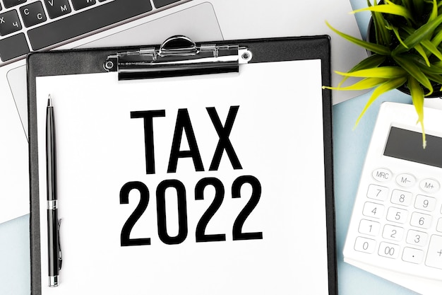 TAX 2022. Klembord, rekenmachine, laptop. Boekhoudkundig concept. Plat leggen.