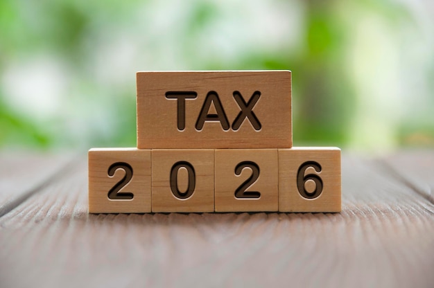 Tax 2026 text on wooded blocks with blurred nature background Taxation and filing concept