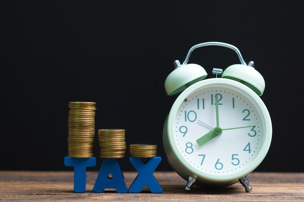 TAX alphabet with stack of coin and vintage alarm clock