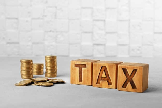 Tax concept with cubes and coins on light background