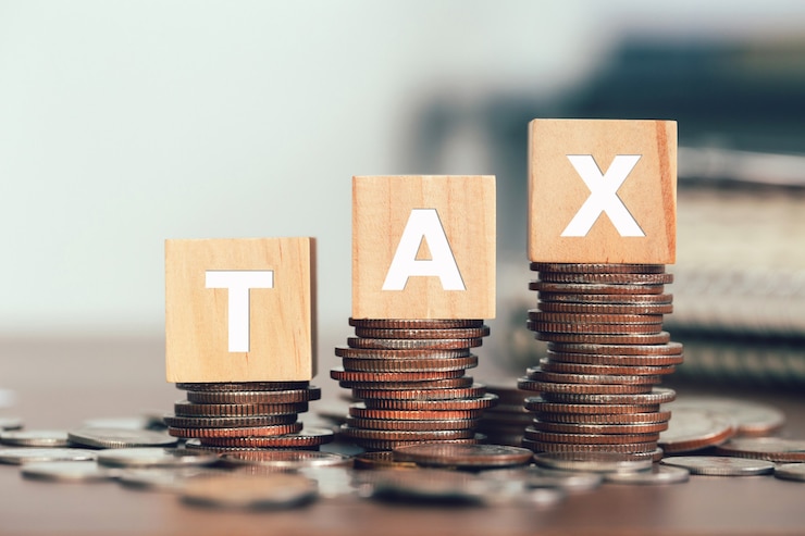 Photo tax concept with wooden cubes with the word tax on stacked coins