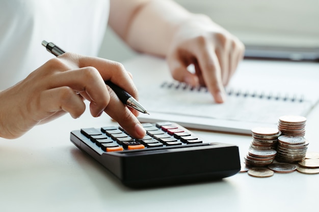 Tax concept.Woman hand using calculator and writing make note with calculate about cost at home office.Work from home