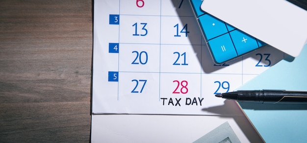 Giorno fiscale del mese. pennarello, calcolatrice, nota adesiva sul calendario