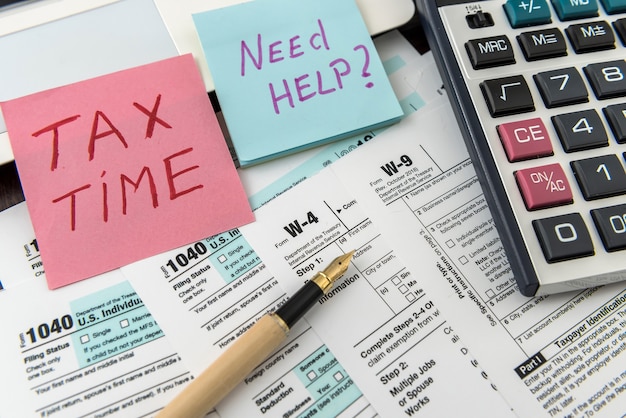 ペンと電卓を備えた税務財務フォームと、Tax Time というテキスト付きのステッカー