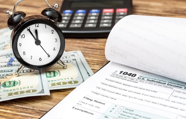 Tax form with money clock and calculator on the desk